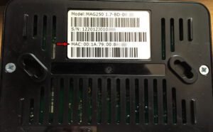 Close-up of a MAG Box showing its MAC address on the settings screen, with a network cable connected.